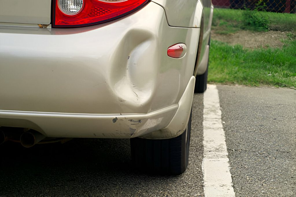 Technician using PDR tools to remove a creased dent from a car panel."