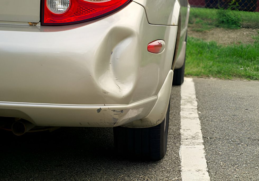 Technician using PDR tools to remove a creased dent from a car panel."