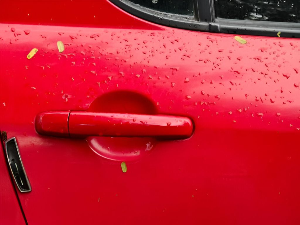 "Car door with a minor dent being repaired using Paintless Dent Repair tools."