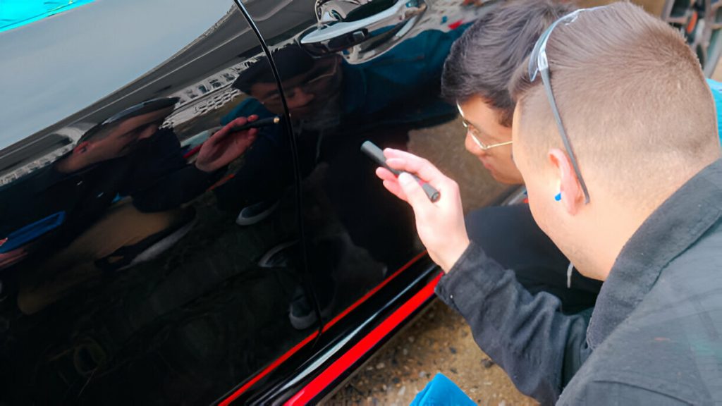 "Technician carefully removing paint transfer from a car door."