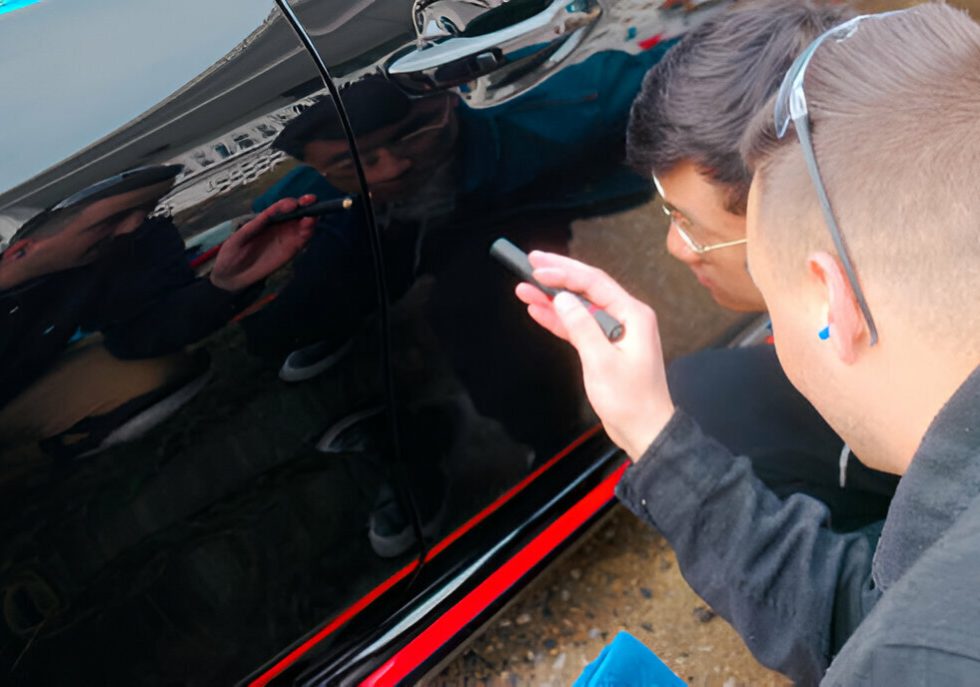 "Technician carefully removing paint transfer from a car door."