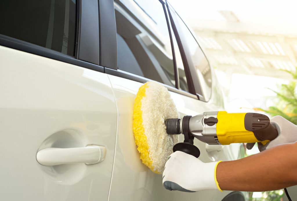 A technician performing paintless dent repair on a car’s door panel."