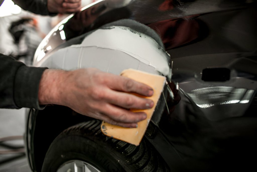 "A technician using PDR tools to remove a dent from a car panel."