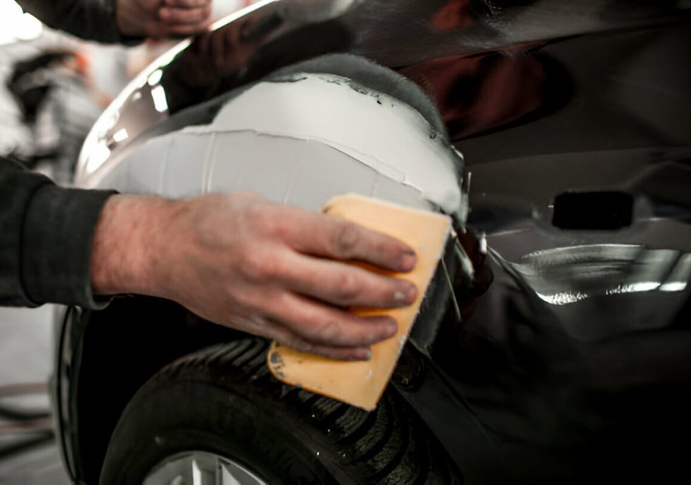 "A technician using PDR tools to remove a dent from a car panel."